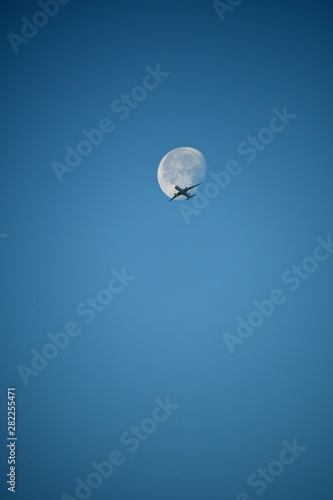 Aeroplane and the moon in a blue sky background