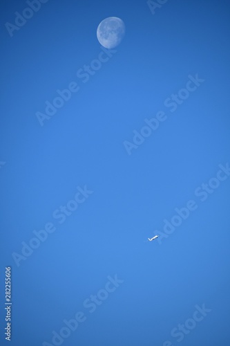 Aeroplane and the moon in a blue sky background