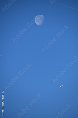 Aeroplane and the moon in a blue sky background