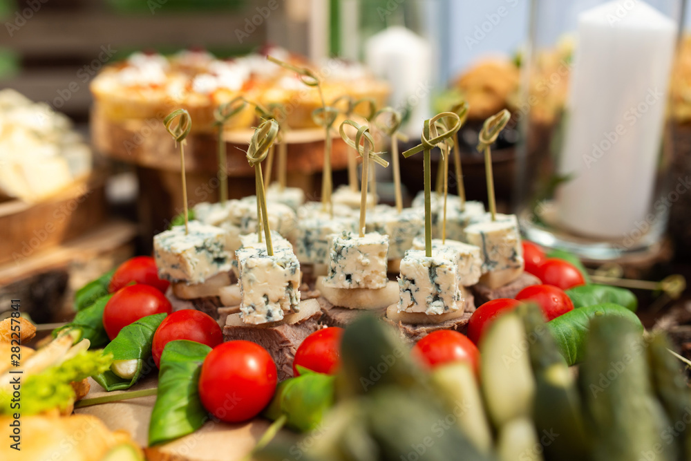 Tasty meals on a brown rustic wooden banquet table. Summer wedding in the forest