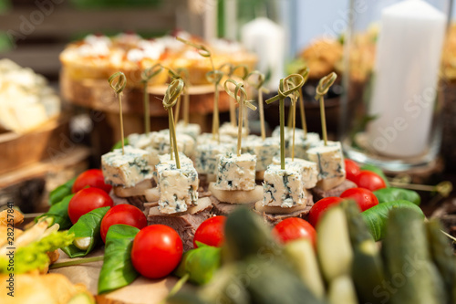 Tasty meals on a brown rustic wooden banquet table. Summer wedding in the forest