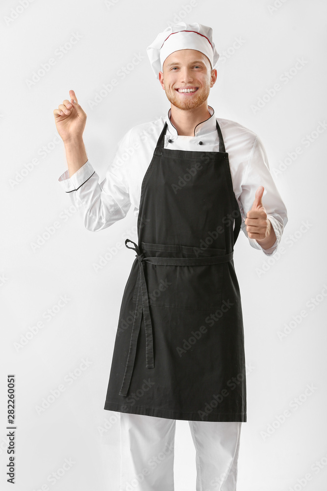 Handsome male chef showing thumb-up and pointing at something on white background Handsome male chef showing thumb-up and pointing at something on white background