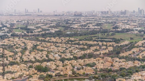 Aerial view of apartment houses and villas with golf course in Dubai city timelapse near jumeirah lake towers district, United Arab Emirates. Top fiew from skyscraper photo