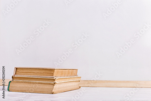 Books on the table against the background of a white board. Copy space.