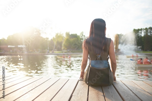      Girl sitting on pier and lookingat the river                photo