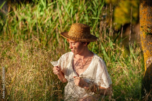 WELLNESS, RELAXATION, WOMAN WITH A STRAW HAT IN THE GRASS IN THE COUNTRYSIDE.