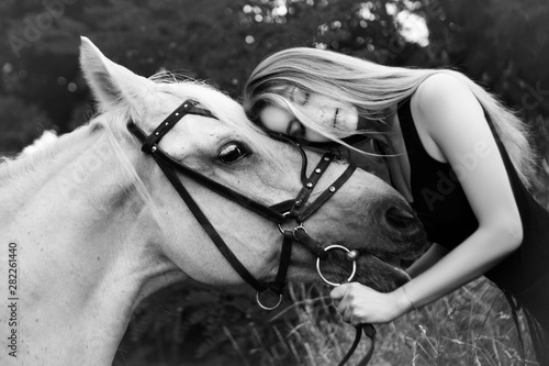 Young beautiful woman hugs a white horse. Black and white photography 