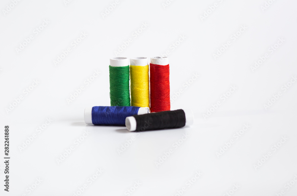 Threads of different colors with the coils in a row and swing needle on white background Threads of different colors with the coils in a row and swing needle on white background