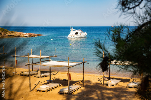 Billede på lærred Secluded mediterranean sandy beach, with yacht at sea horizon.