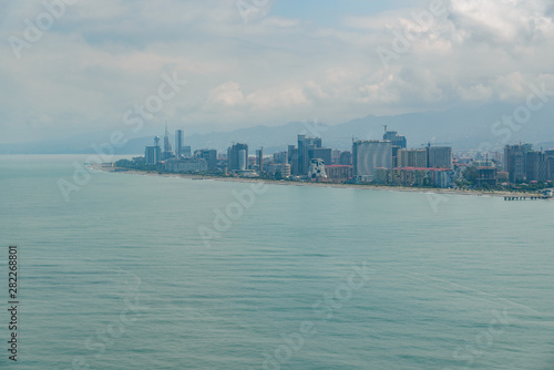 view from the airplane porthole to the resort town of Batumi located in Georgia, on a sunny day with clouds in the sky.