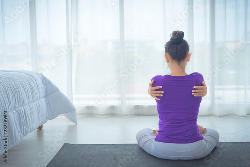Fototapeta Naklejka Na Ścianę i Meble -  A beautiful young woman sitting in a yoga room in a calm and relaxed manner. Light, comfortable, light window background comes in the morning. Health care concepts