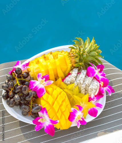 Fruit plate with delicious and fresh local asian pineapple, mango, grapes and dragon fruit (pitaya or pitahaya) on the luxury sailing yacht on a cruise between Phuket and Phi Phi islands, Thailand
