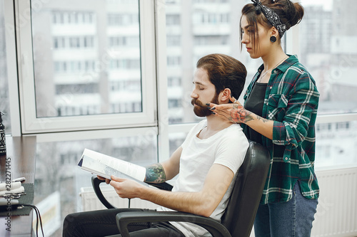 Man with a beard. Hairdresser with a client. Woman with a comb and scissors