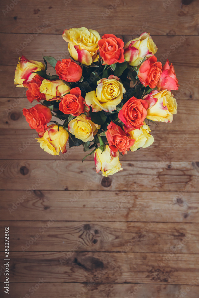 Bouquet of roses on a wooden background. View from above. Bouquet of flowers on the table. Yellow and orange roses.