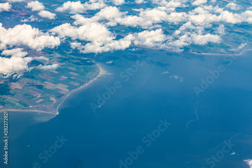 .top view on clouds and earthtop view through clouds to land and sea