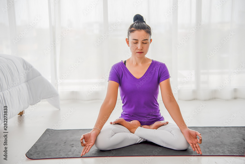 A beautiful young woman sitting in a yoga room in a calm and relaxed manner. Light, comfortable, light window background comes in the morning. Health care concepts A beautiful young woman sitting in a yoga room in a calm and relaxed manner. Light, comfortable, light window background comes in the morning. Health care concepts