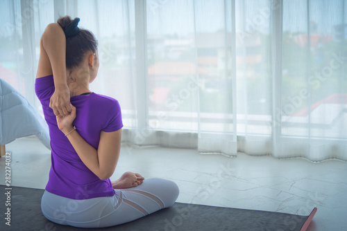 A beautiful young woman sitting in a yoga room in a calm and relaxed manner. Light, comfortable, light window background comes in the morning. Health care concepts