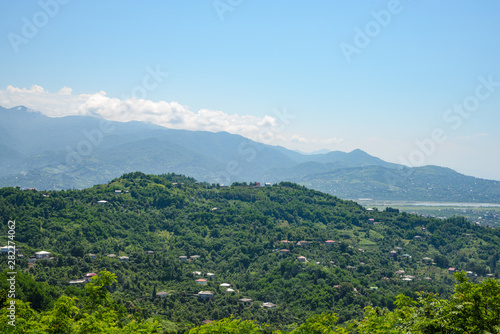 view of a mountain village located on a mountainside on a bright sunny day, with clouds in the sky.