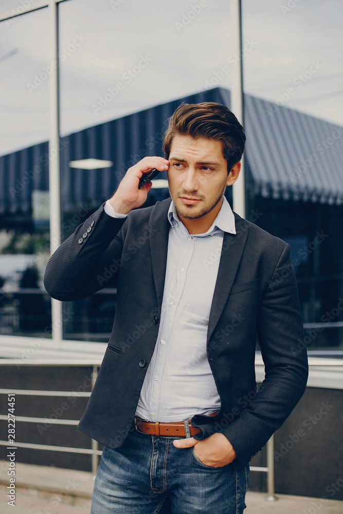 Man in a stylish suit. Businessman in a summer city. Male use the phone Man in a stylish suit. Businessman in a summer city. Male use the phone