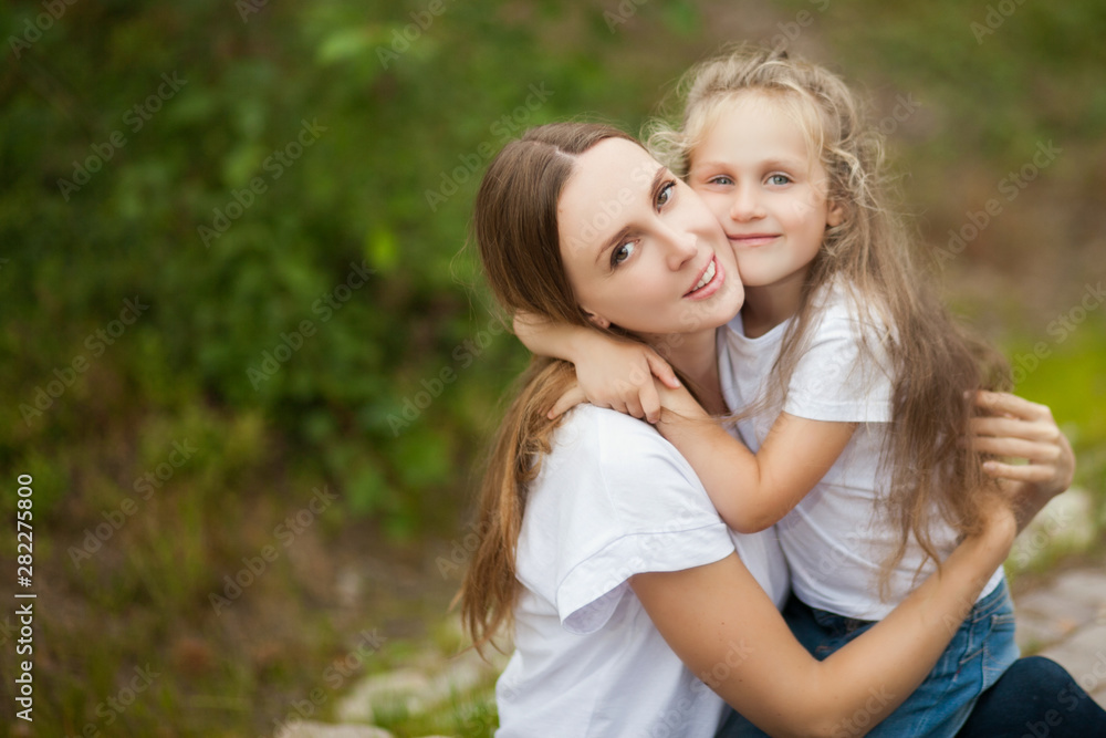 Happy smiling mother and daughter child are hugging and having fun outdoor in nature