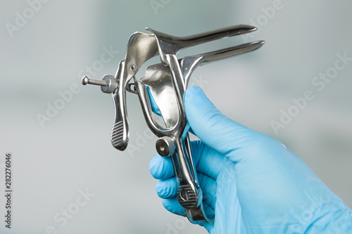 doctor's hand in medical gloves presents a medical speculum