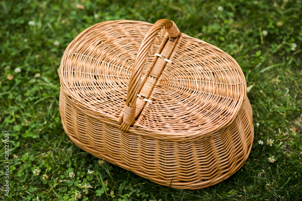 Fototapeta premium Wicker picnic basket on grass top view