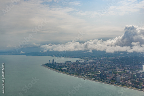 view from the airplane porthole to the resort town of Batumi located in Georgia  on a sunny day with clouds in the sky.