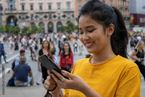 giovane asiatica sorridente durante una conversazione al telefono