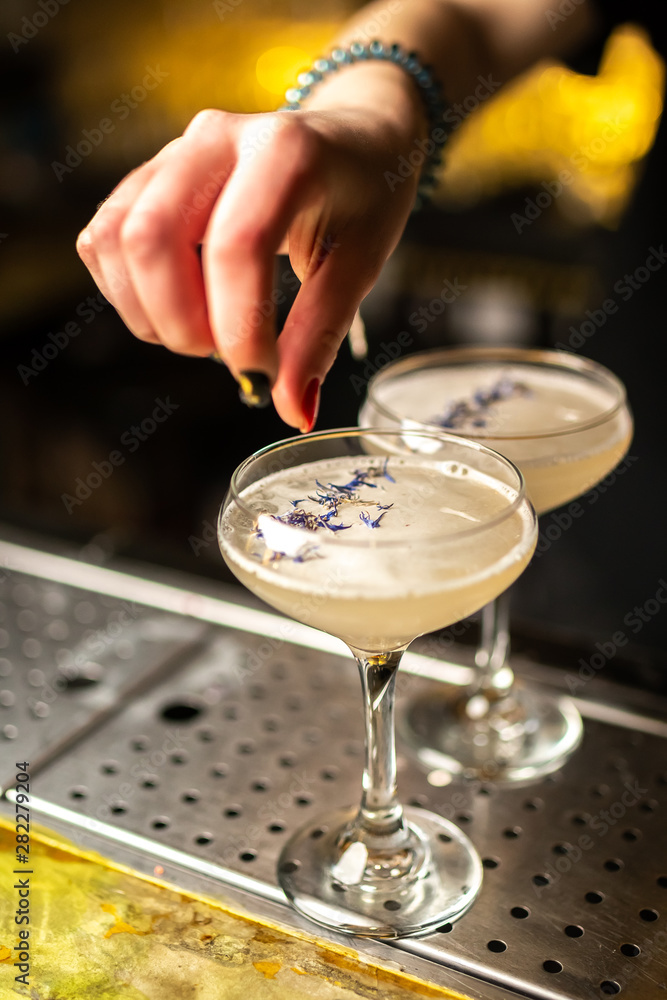 Close-up of expert bartender making cocktail on the bar, blurred background.