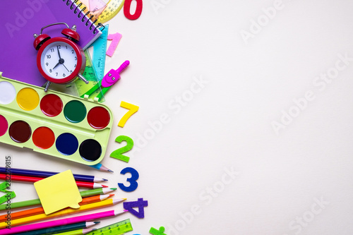 Colored different school supplies on light paper background. Back to school concept. Flat lay, top view, copy space