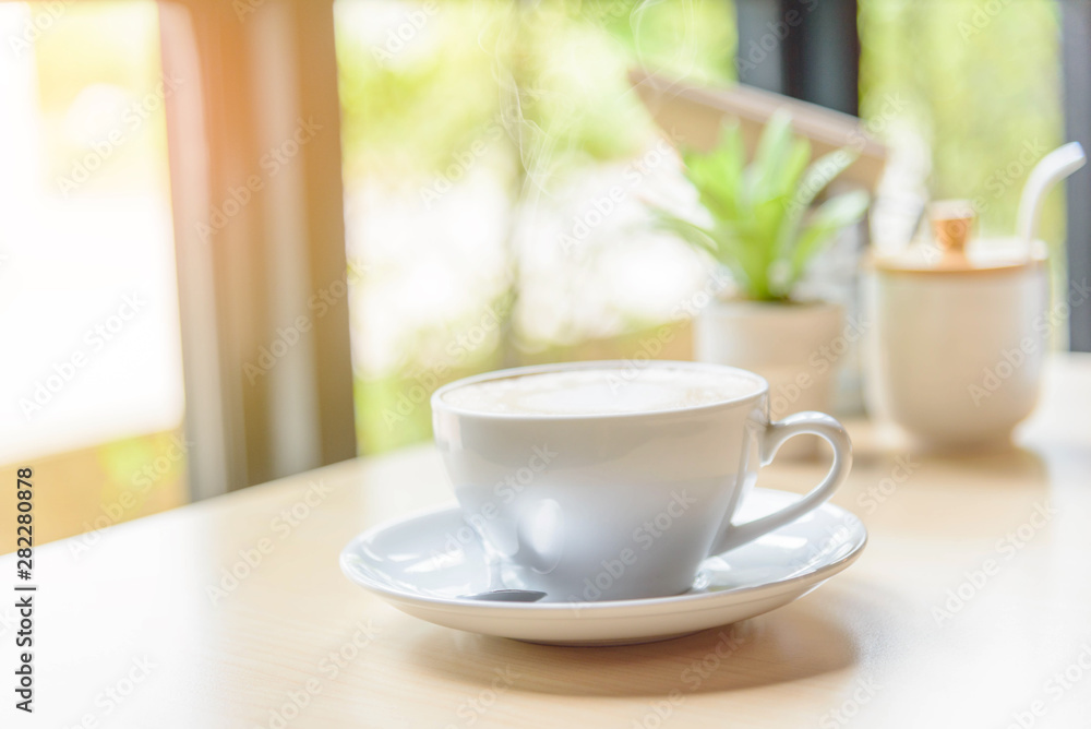 hot coffee on table with sunlight / hot cappuccino with nice pattern milk foam 