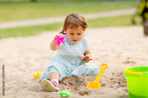 childhood, leisure and people concept - little baby girl plays with toys in sandbox © Syda Productions