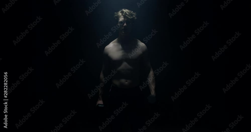 Lifting Weights Staring At Camera On Spotlight Preparing For Big Match Wearing White T-shirt Lifting Weights Staring At Camera On Spotlight Preparing For Big Match Wearing White T-shirt