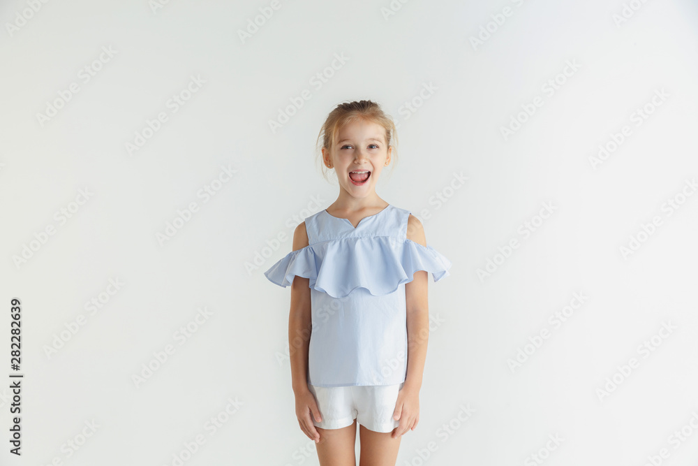 Stylish little smiling girl posing in casual clothes isolated on white studio background. Caucasian blonde female model. Human emotions, facial expression, childhood. Smiling, looking at camera. Stylish little smiling girl posing in casual clothes isolated on white studio background. Caucasian blonde female model. Human emotions, facial expression, childhood. Smiling, looking at camera.