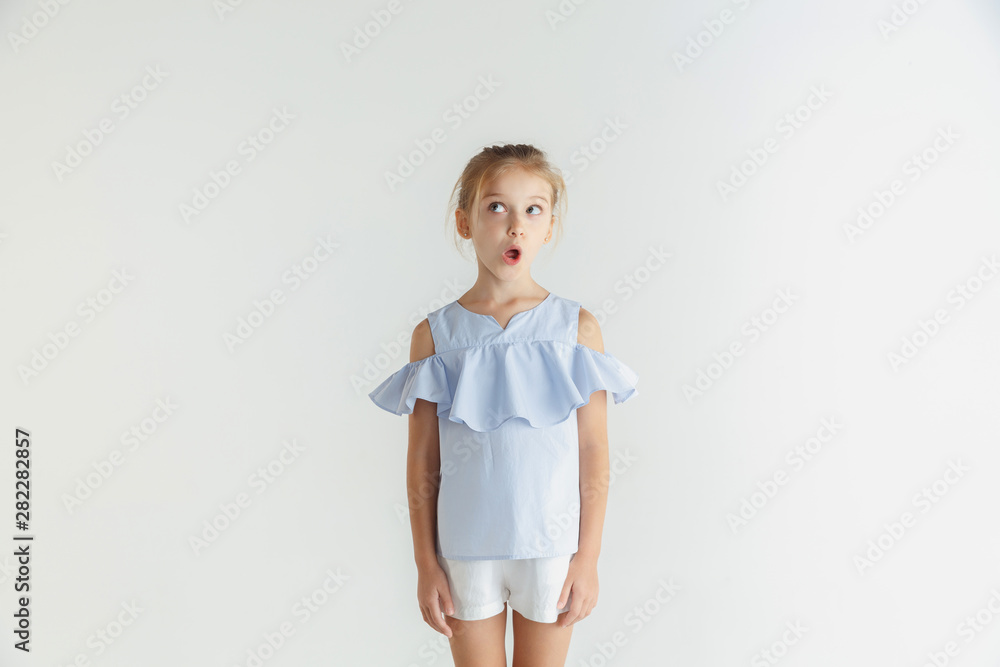Stylish little smiling girl posing in casual clothes isolated on white background. Caucasian blonde female model. Human emotions, facial expression, childhood. Shocked, thoughtful, looking at side. Stylish little smiling girl posing in casual clothes isolated on white background. Caucasian blonde female model. Human emotions, facial expression, childhood. Shocked, thoughtful, looking at side.