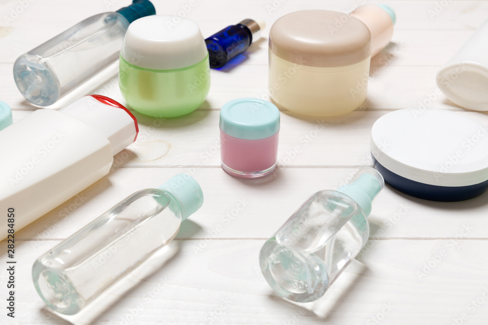 Close-up view of cosmetic bottles, jars, containers and sprays on white wooden background. Beauty concept with copy space Close-up view of cosmetic bottles, jars, containers and sprays on white wooden background. Beauty concept with copy space