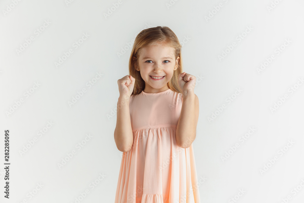 Stylish little smiling girl posing in dress isolated on white studio background. Caucasian blonde female model. Human emotions, facial expression, childhood. Smiling, winning, celebrating. Stylish little smiling girl posing in dress isolated on white studio background. Caucasian blonde female model. Human emotions, facial expression, childhood. Smiling, winning, celebrating.