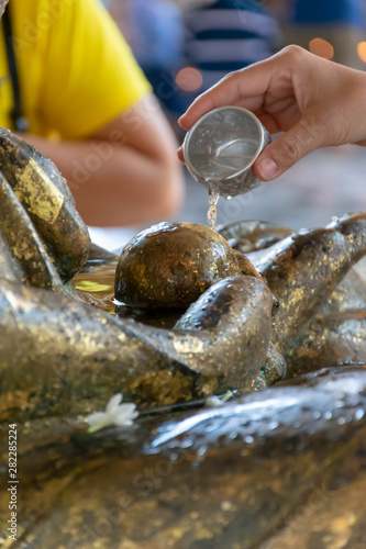Water pouring to Buddha statue in Songkran festival tradition of thailand. (selective focus)