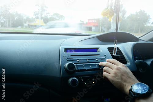 a hand of adult man with black handwatch touching the scan pad to searching the radio station in the car while traveling tour