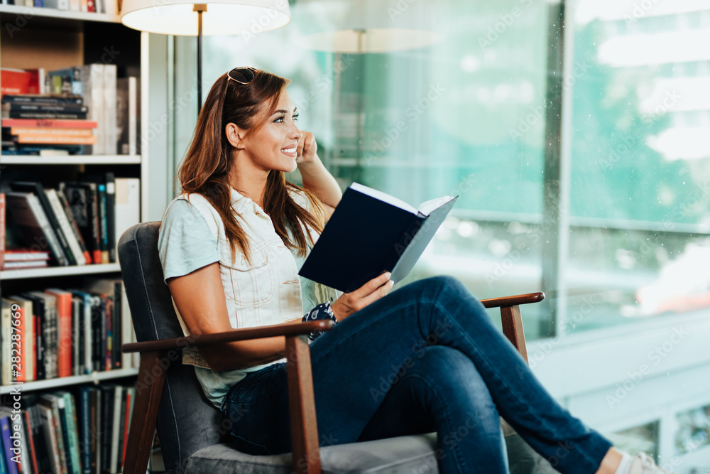 Fototapeta premium Attractive young female student choosing books in the bookstore