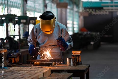 Industrial welder is welding metal part in the factory.