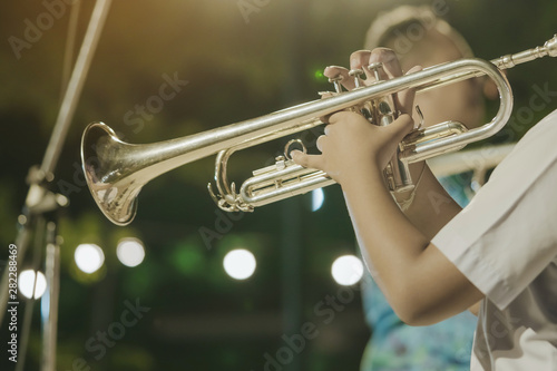 Canvas Print Male student with friends blow the trumpet with the band for performance on stage at night