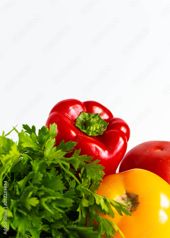fresh ripe vegetables on a white background: bell pepper, parsley, pink and yellow tomatoes fresh ripe vegetables on a white background: bell pepper, parsley, pink and yellow tomatoes