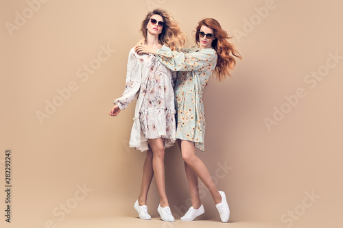 Two fashionable Lovable embracing girl posing in Studio. Beautiful Adorable young woman in Stylish autumnal dress. Trendy curly wavy hair, make up. Sister friend, fashion beauty autumn concept