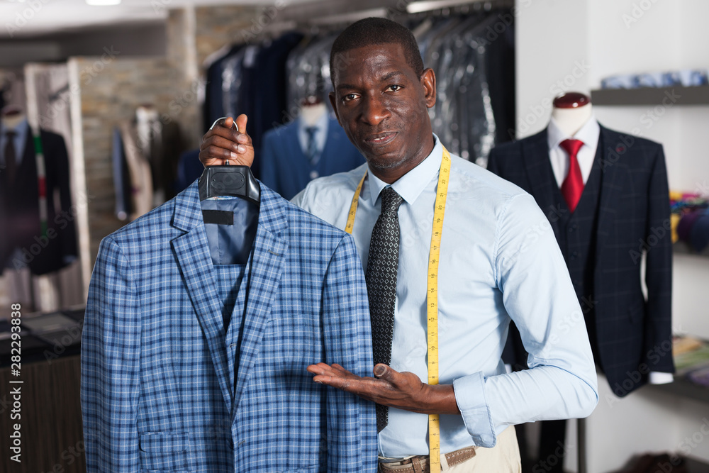 Male tailor demonstrating of fashionable suit in apparel shop
