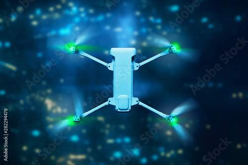 Drone quadcopter flying above city at night
