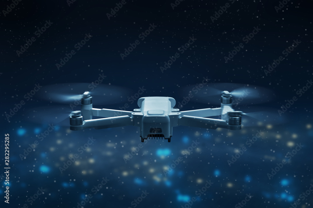 Drone quadcopter flying above city at night