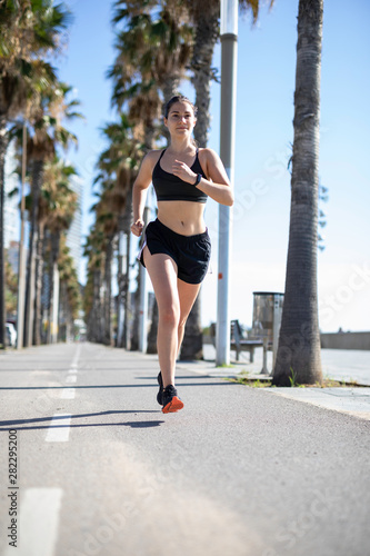 Beautiful woman in sport clothes running on the bike lane at the seafront in Barcelona (SPAIN) © Gabriel