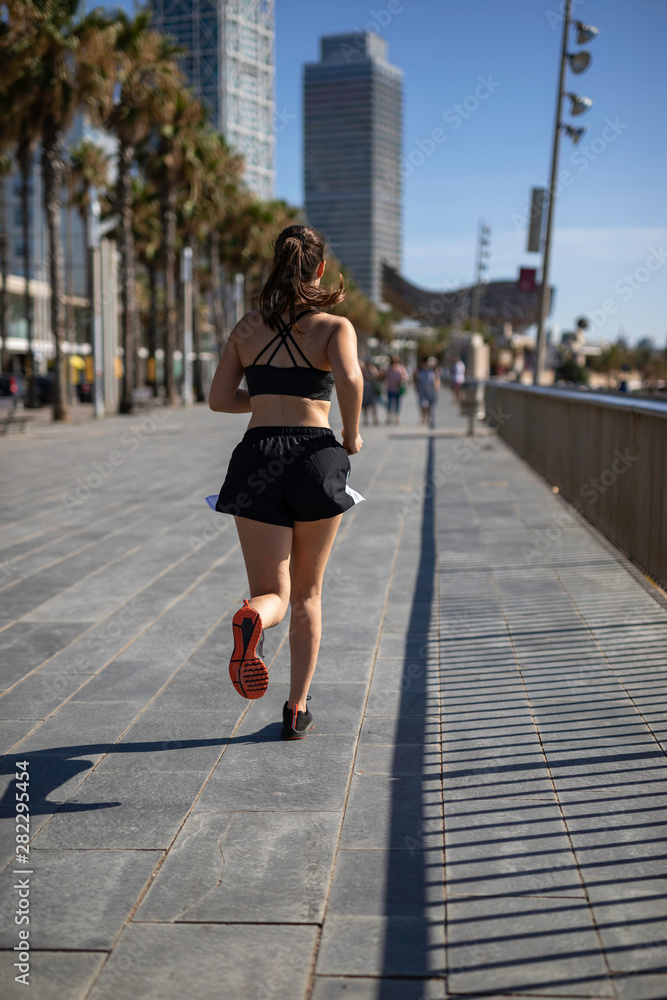 Beautiful woman in sport clothes running on the seafront in Barcelona (SPAIN)