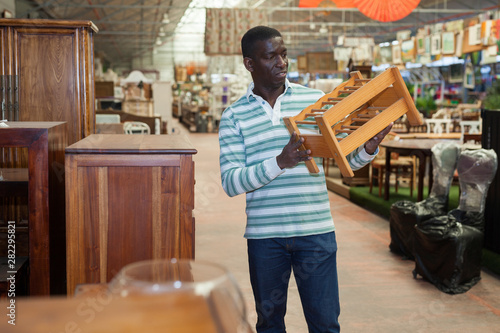African American searching of wooden furniture in store